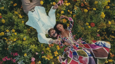 a man and a woman laying in a field of flowers