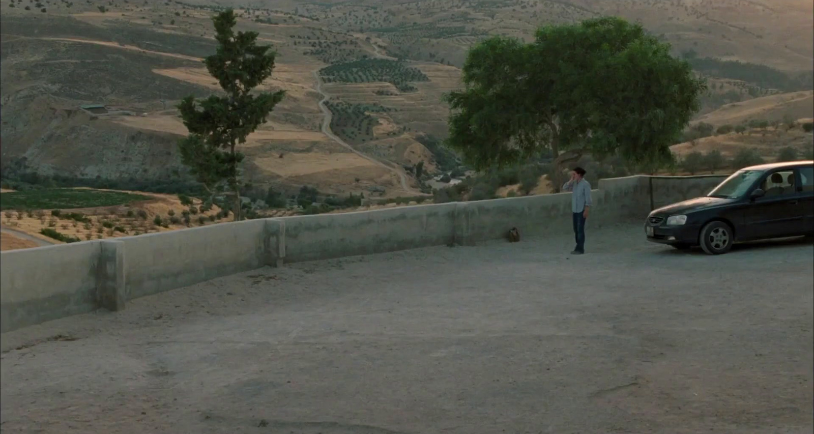 a person standing next to a car on a dirt road