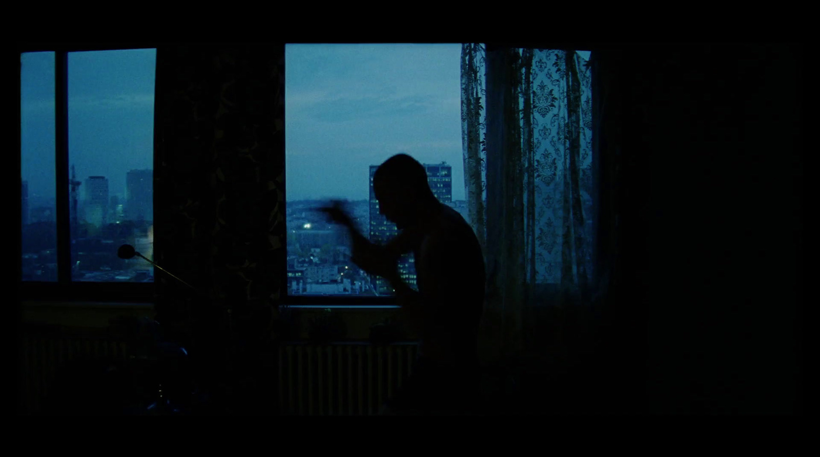 a man standing in front of a window in a dark room