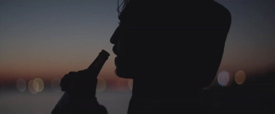 a silhouette of a person holding a bottle in their hand