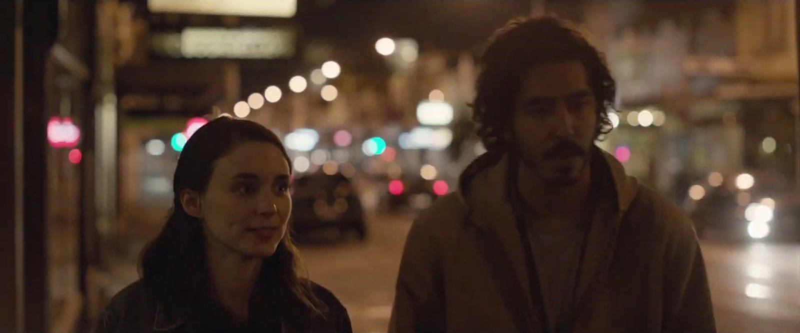 a man and a woman walking down a street at night