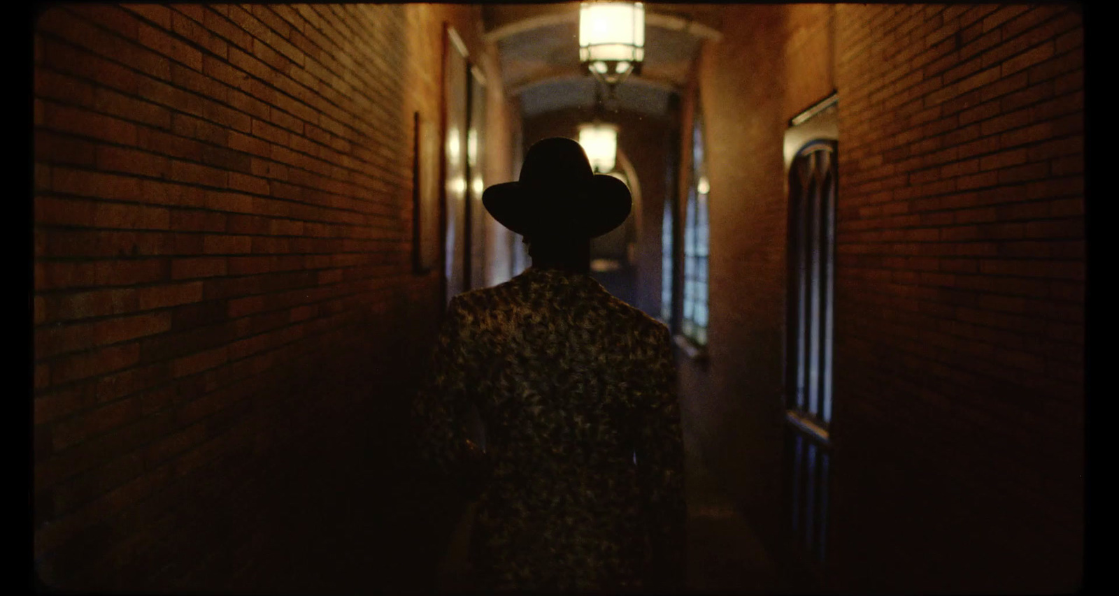 a person with a hat walking down a hallway