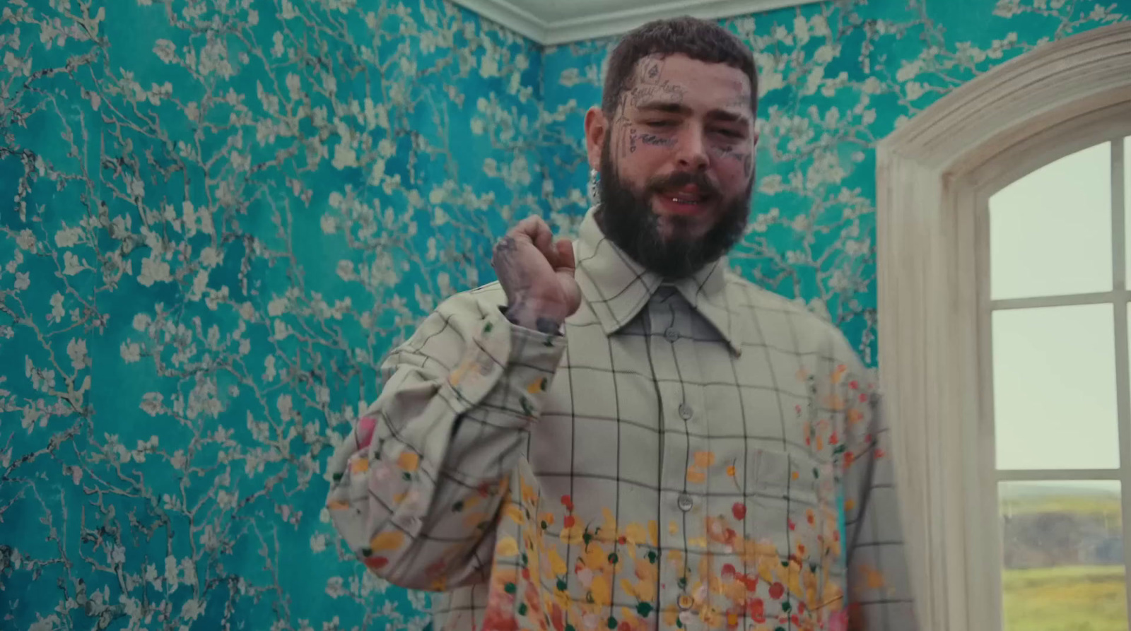 a man with a beard standing in front of a window