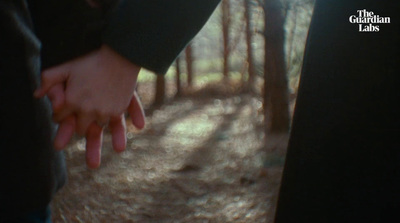 a person holding the hand of another person in a forest