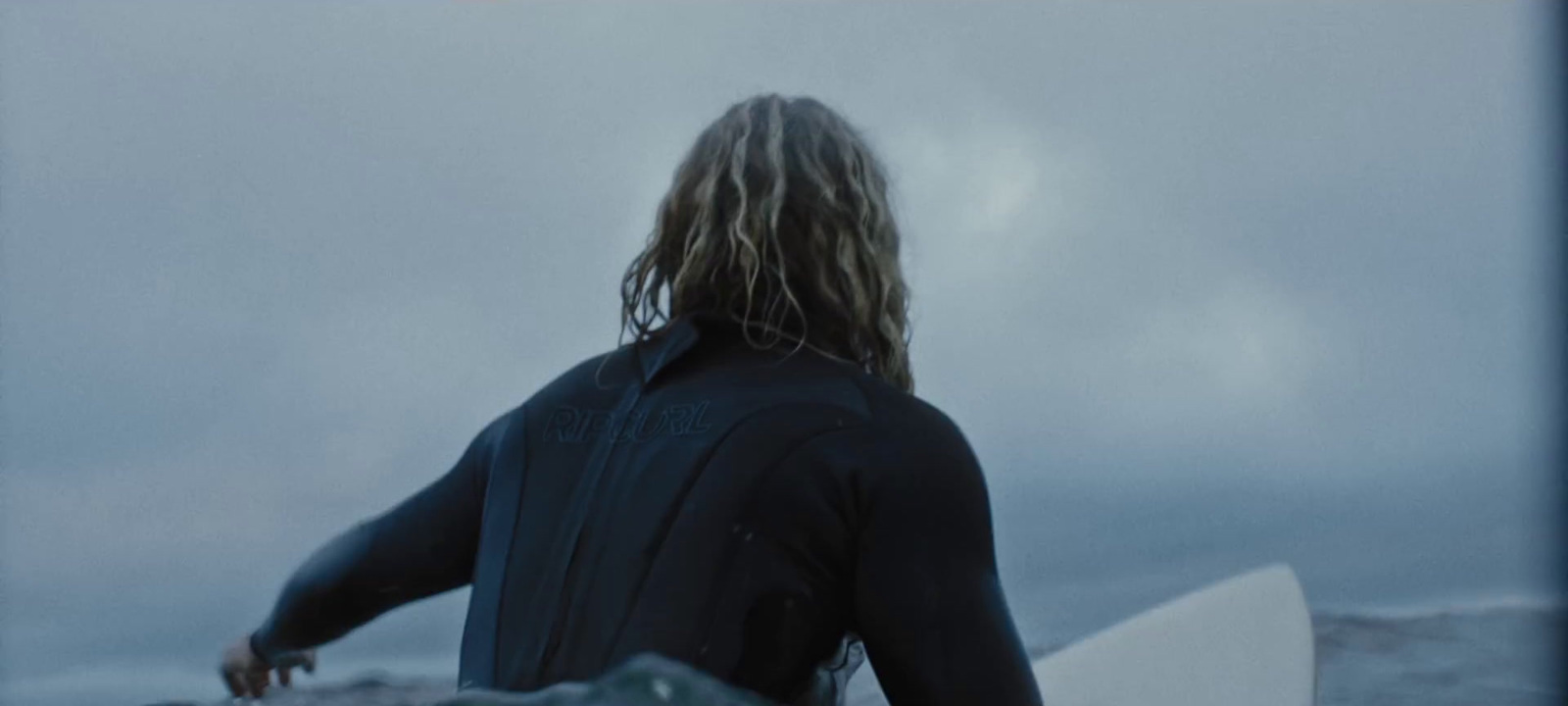 a man in a wet suit holding a surfboard