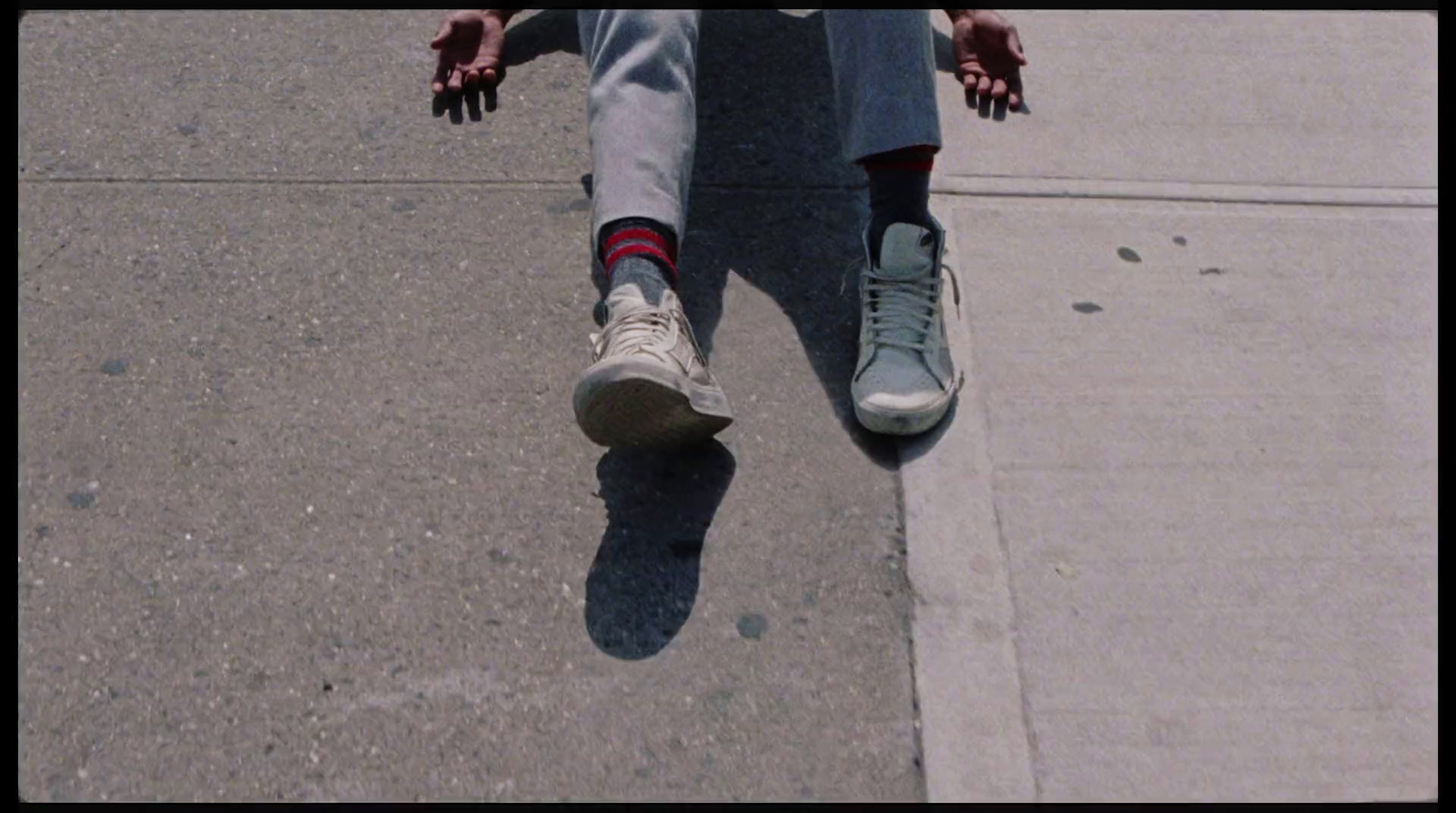 a person sitting on a curb with their feet on a skateboard