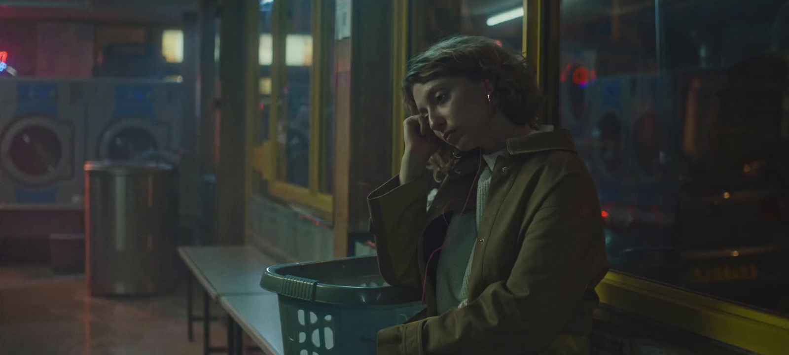 a woman talking on a cell phone next to a trash can