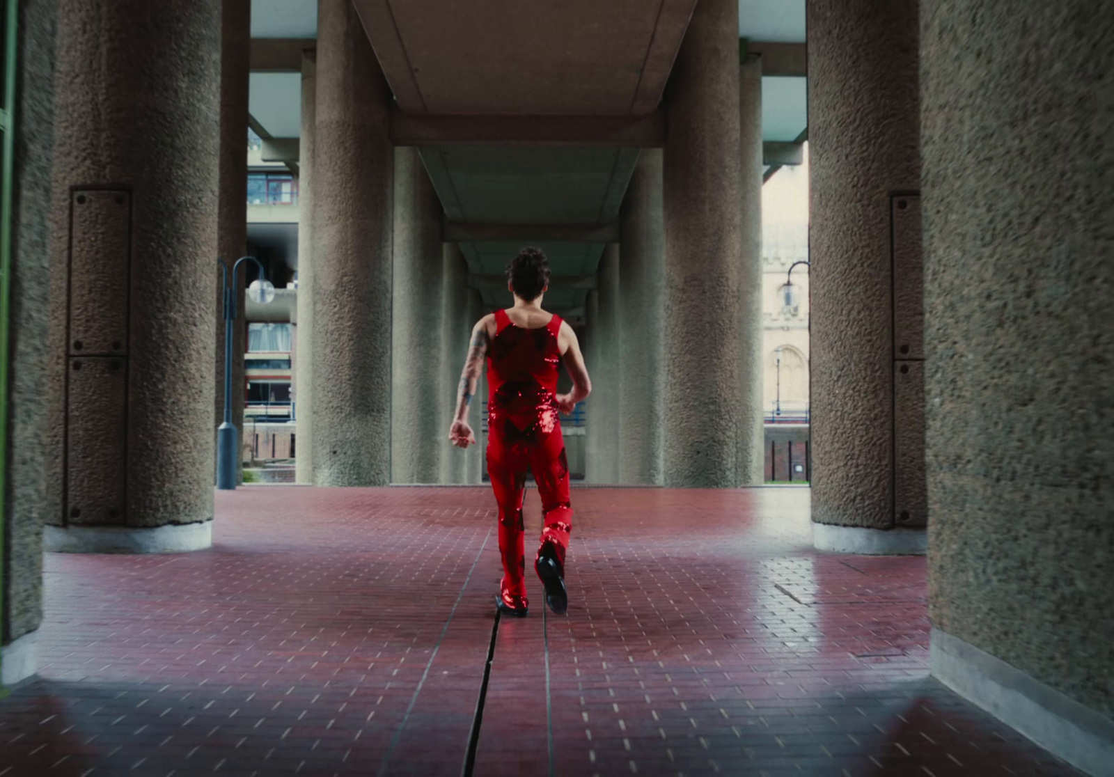 a man in a red outfit walking down a hallway