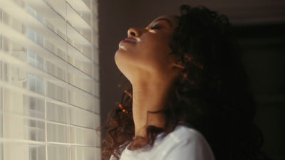 a woman standing next to a window looking up