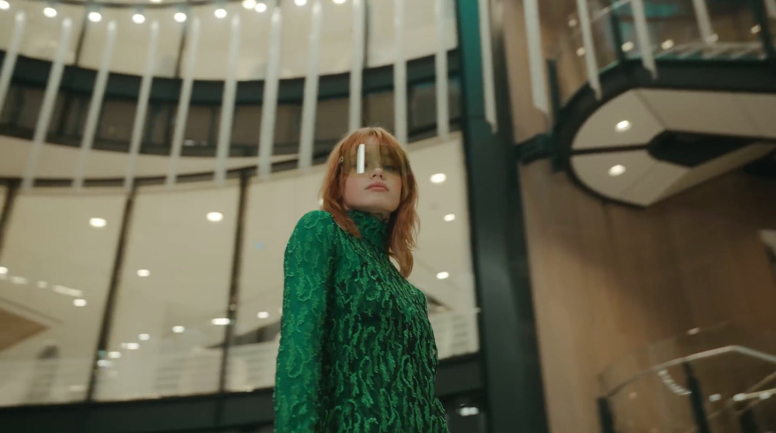 a woman in a green dress standing in front of a clock