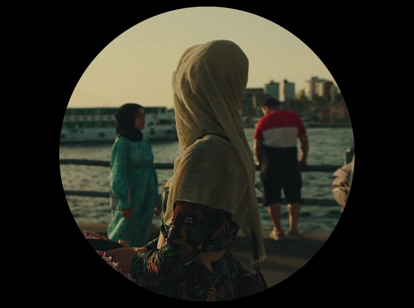 a woman in a headscarf standing next to a body of water