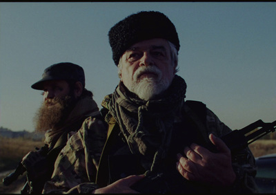 a man with a beard holding a gun next to another man