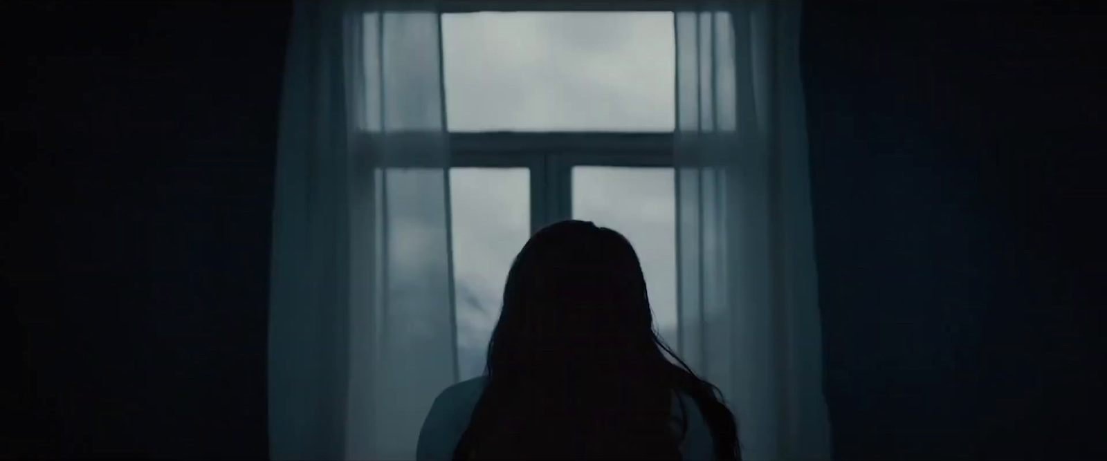 a woman standing in front of a window in a dark room