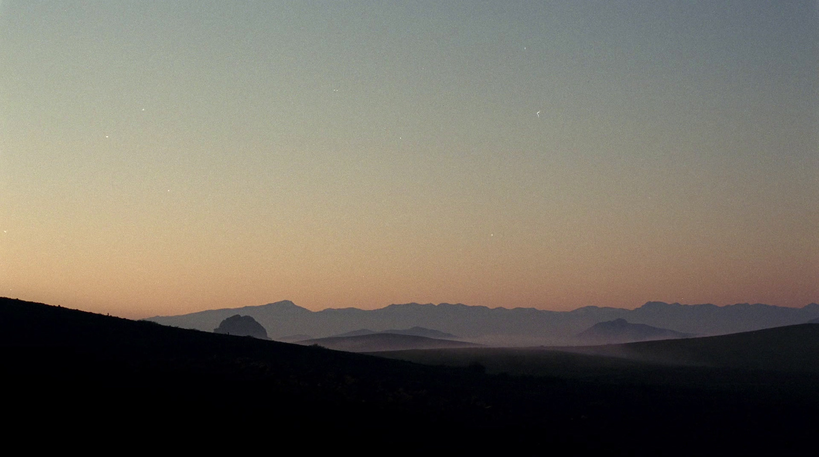 a distant view of a mountain range at sunset