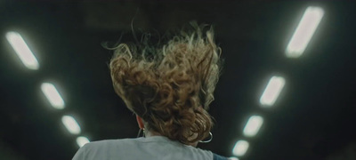 a woman with curly hair standing in a tunnel