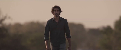 a man walking in a field with trees in the background