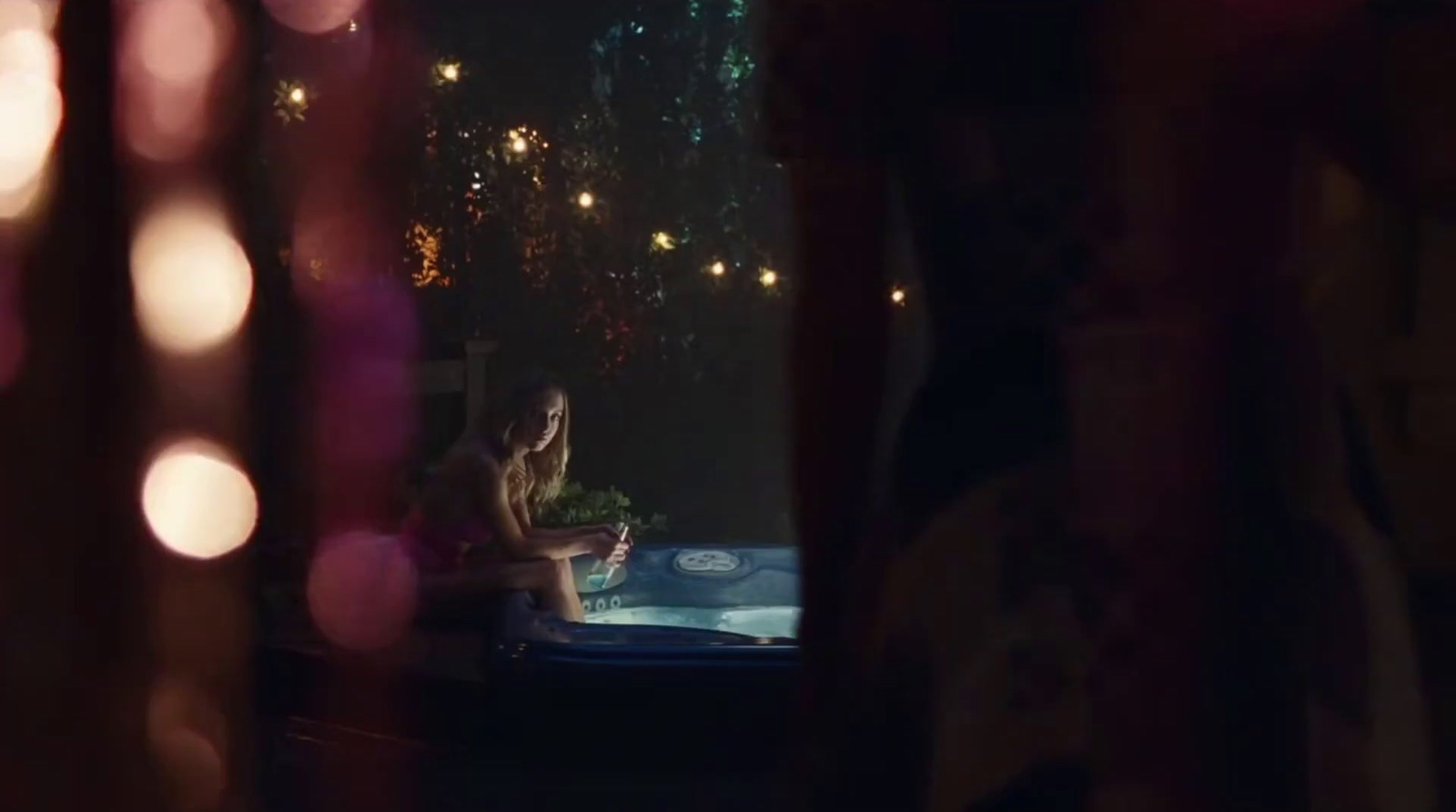 a woman is sitting in a hot tub at night