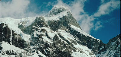 a large mountain covered in snow under a blue sky