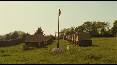 a couple of tents in a field with a flag pole