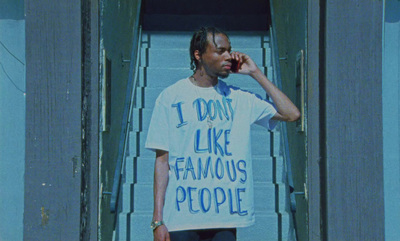 a man talking on a cell phone while wearing a t - shirt that says i