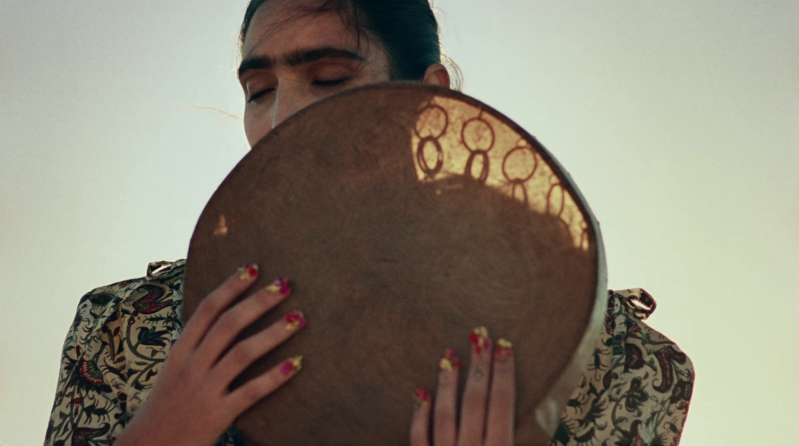 a woman holding a large brown drum with writing on it