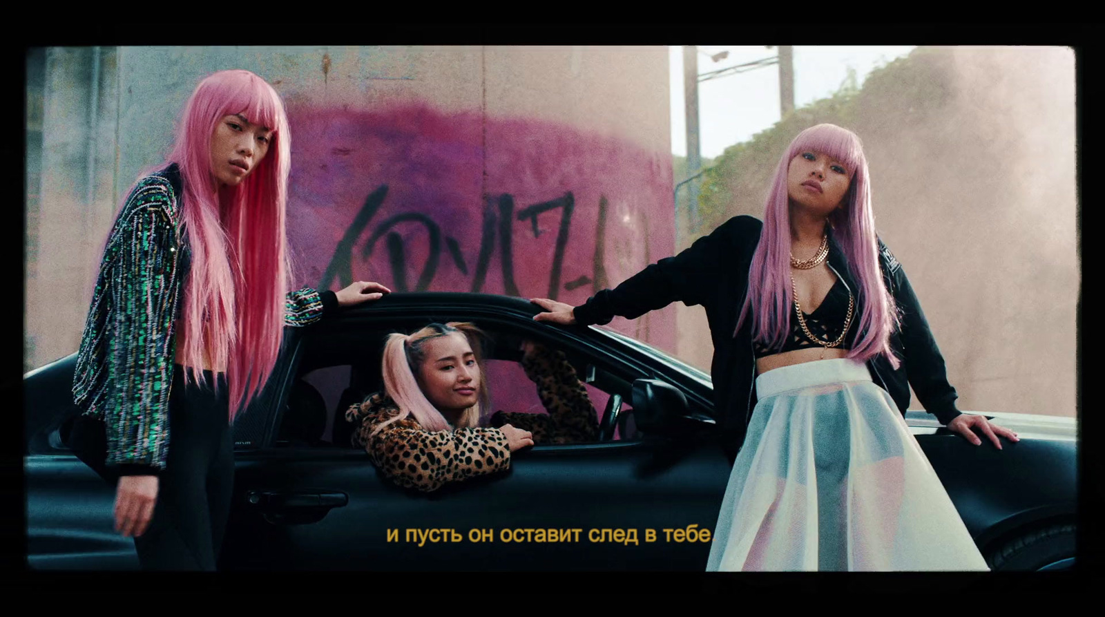 two women with pink hair standing next to a car