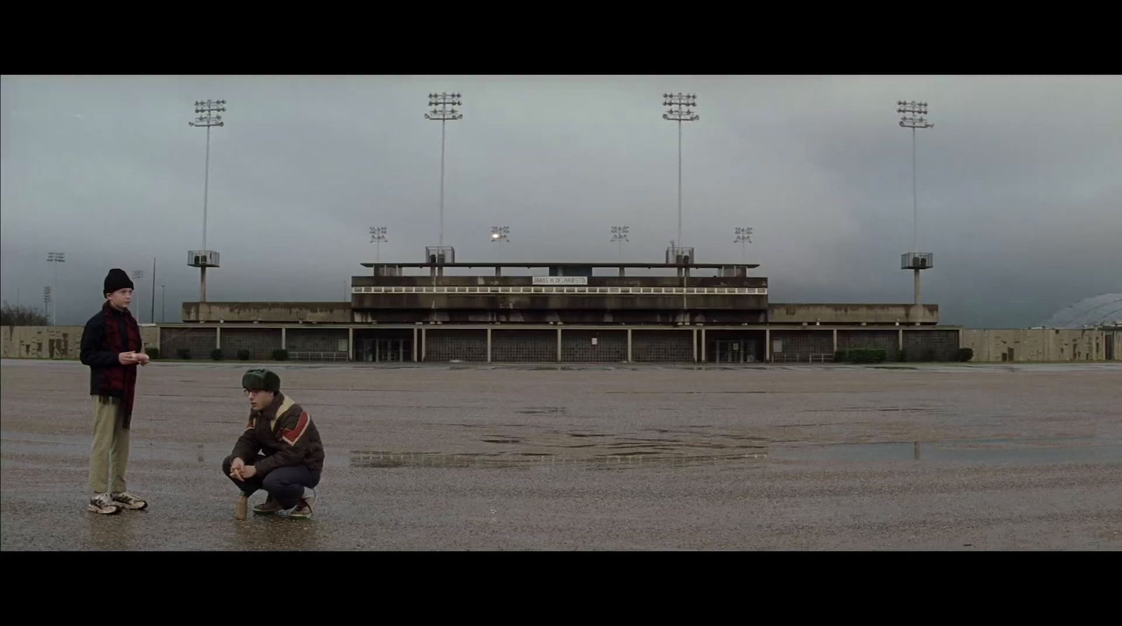 a couple of men standing on top of a wet field