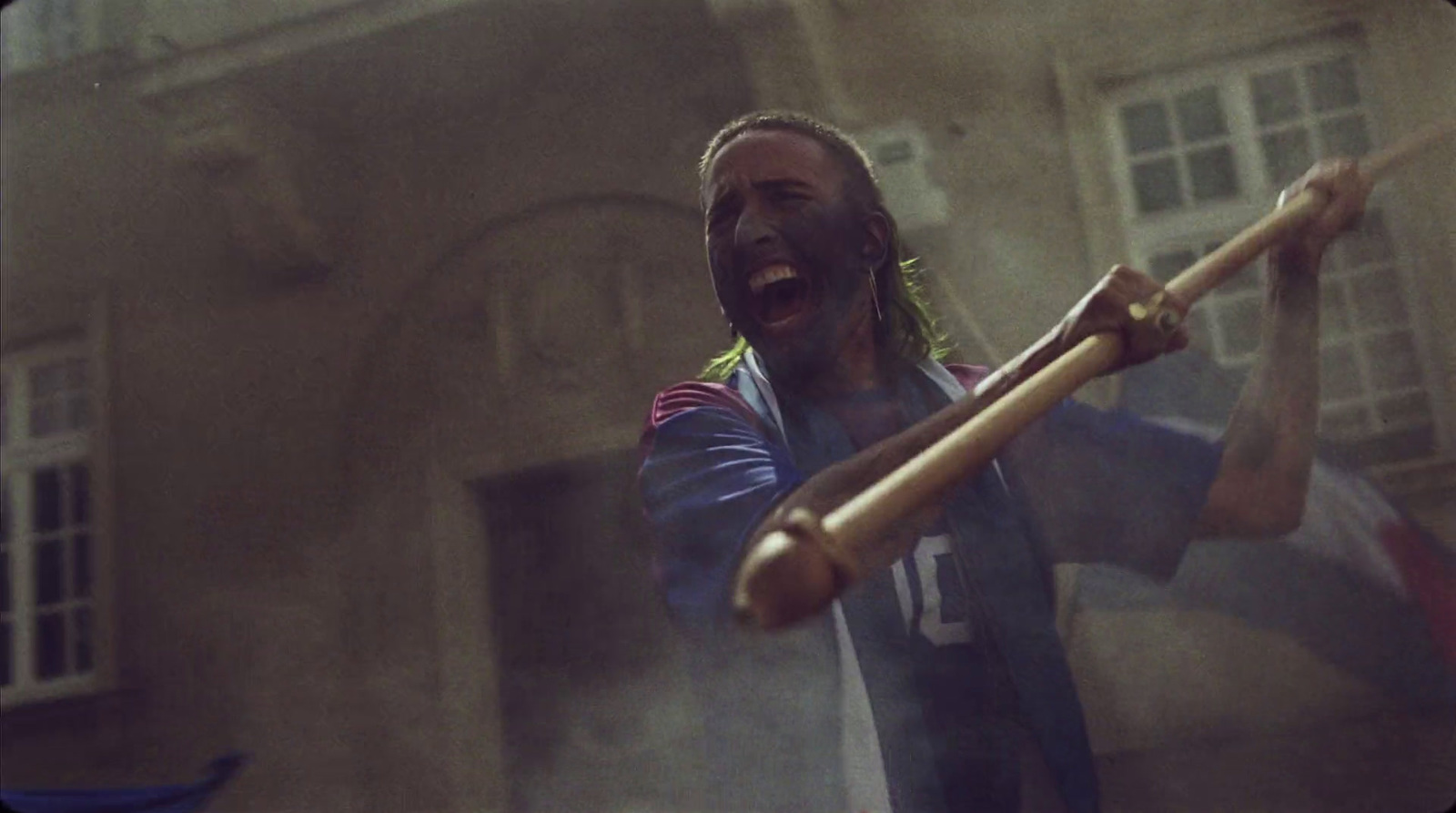 a man holding a baseball bat in front of a building