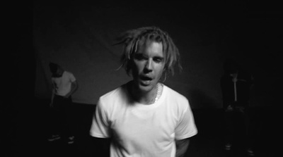 a man with dreadlocks standing in a dark room