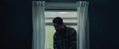 a man standing in front of a window in a dark room