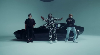 three people standing in front of a car