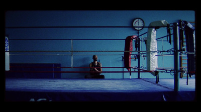 a person sitting in a boxing ring with a clock on the wall