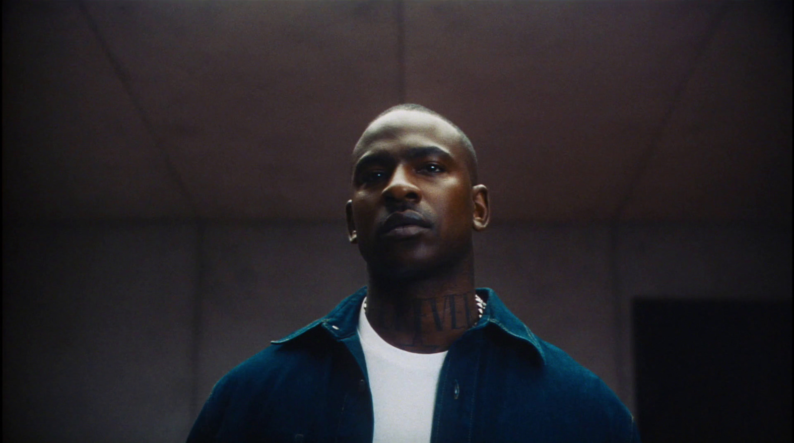 a man with piercings on his neck standing in a room