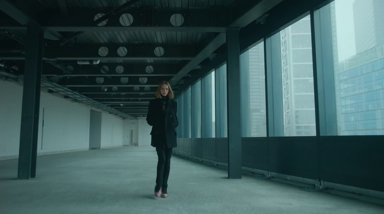 a woman standing in an empty room with large windows