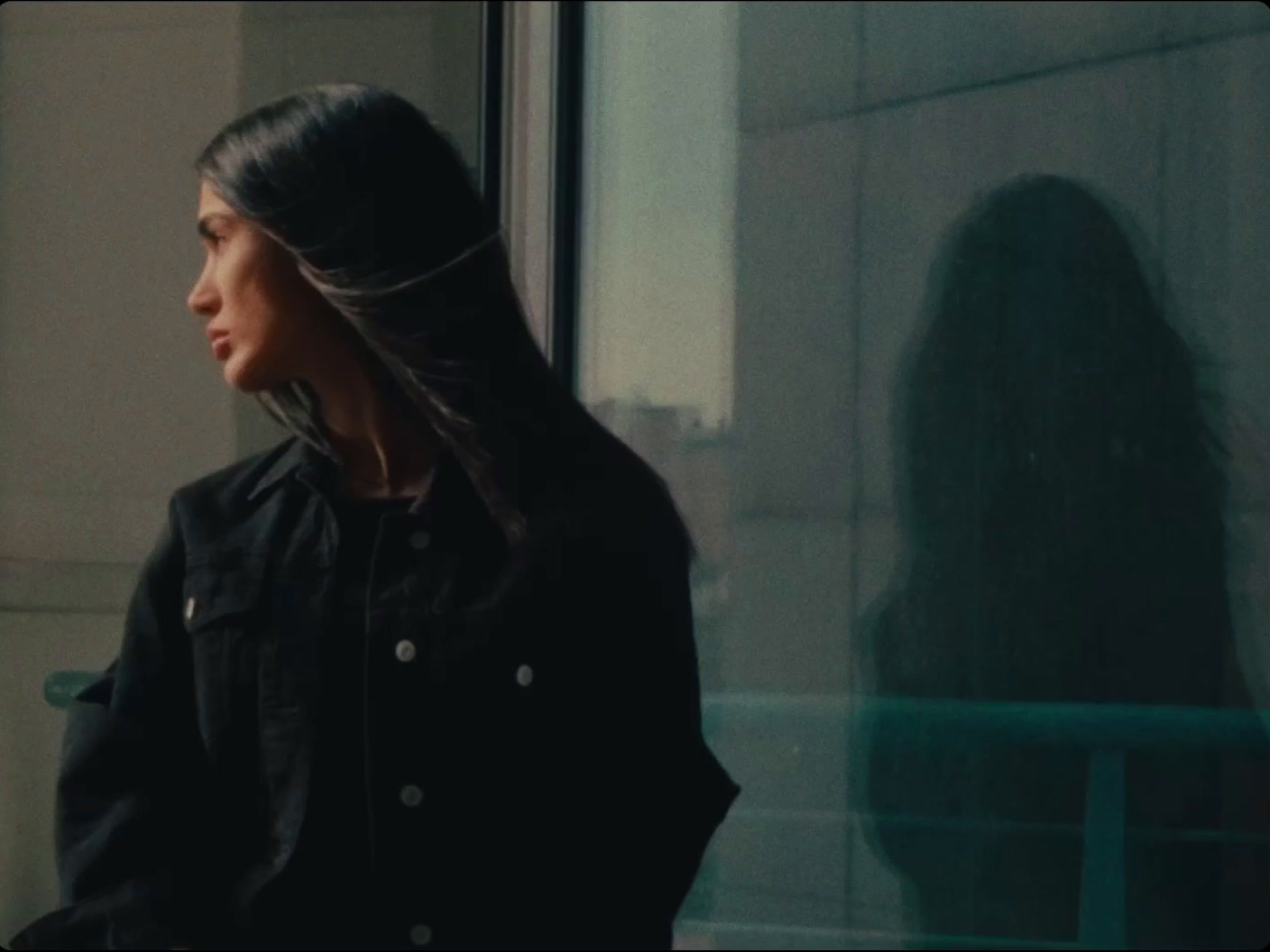 a woman standing in front of a window next to a building