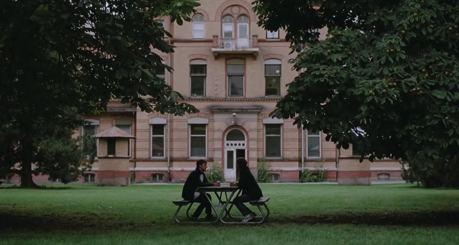 two people sitting at a table in front of a large building