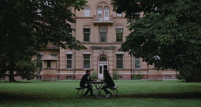 two people sitting at a table in front of a large building