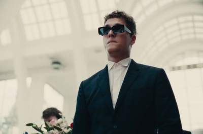 a man in a suit and sunglasses standing in a building