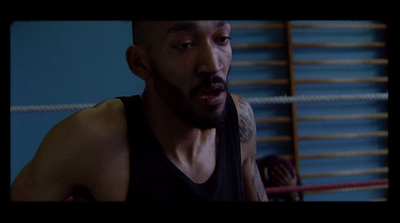 a man in a black tank top standing in front of a boxing ring