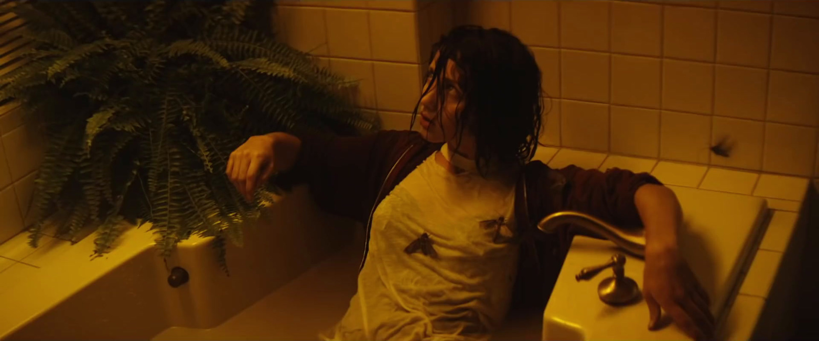 a woman standing in a bathroom next to a plant