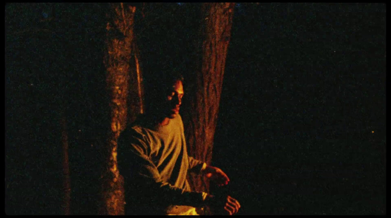 a man standing next to a tree in the dark