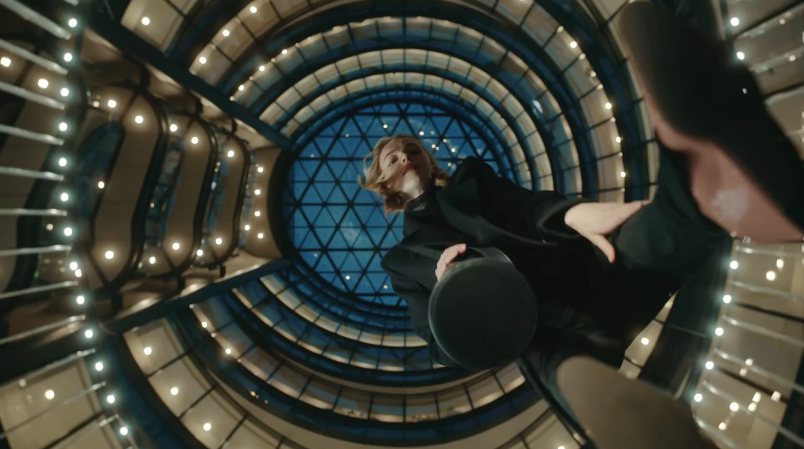 a woman in a black dress is standing in a spiral staircase