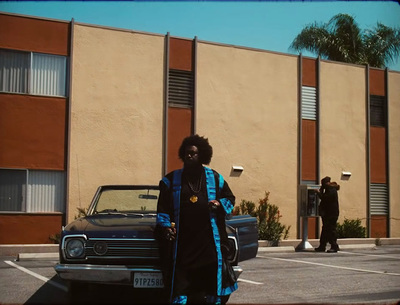 a woman in a black and blue outfit standing in a parking lot next to a