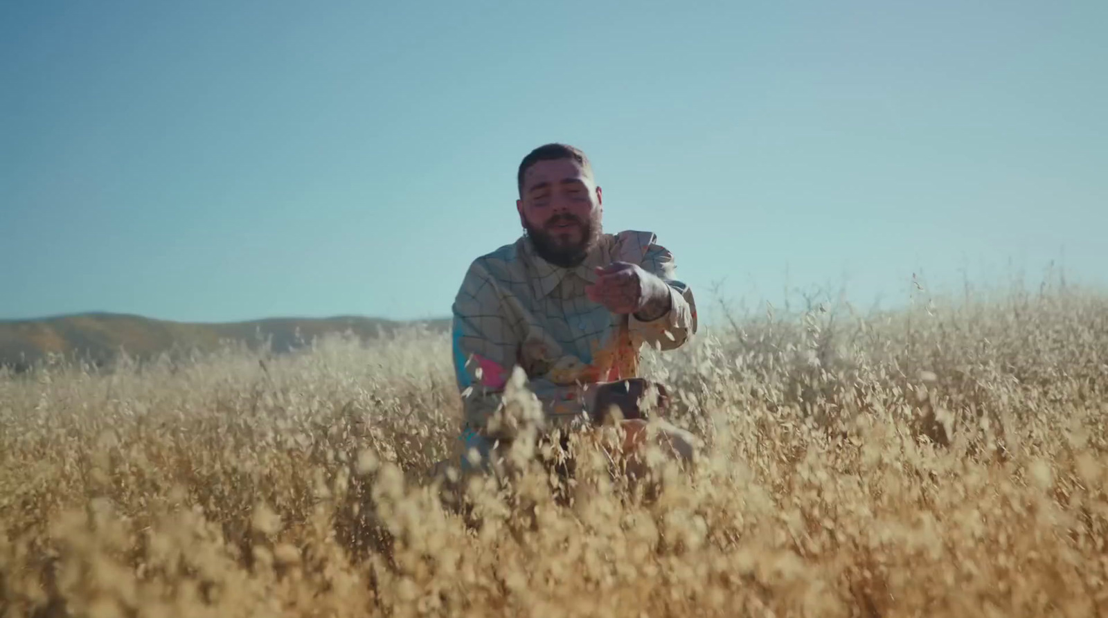 a man holding a baby in a field of tall grass