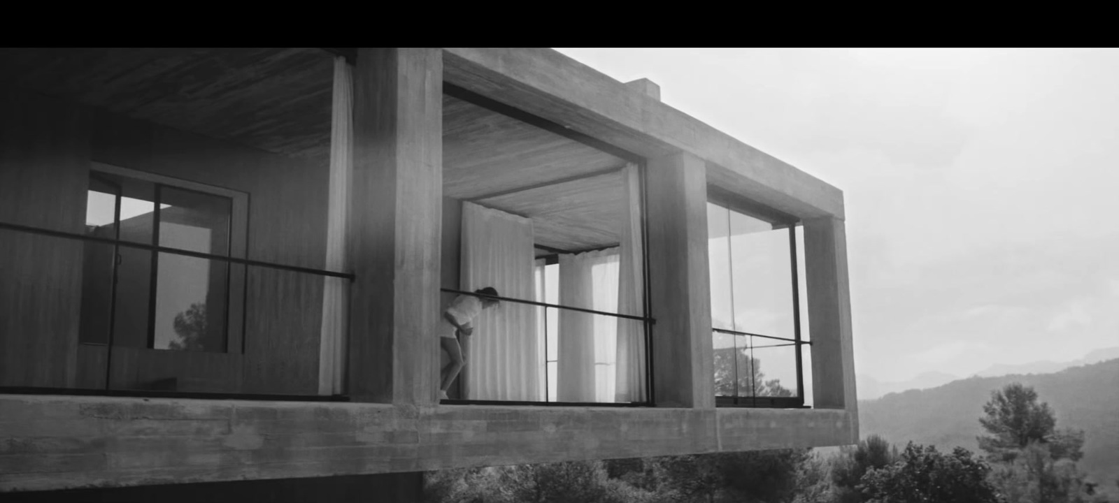 a black and white photo of a person looking out of a window