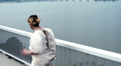 a woman walking across a bridge over water