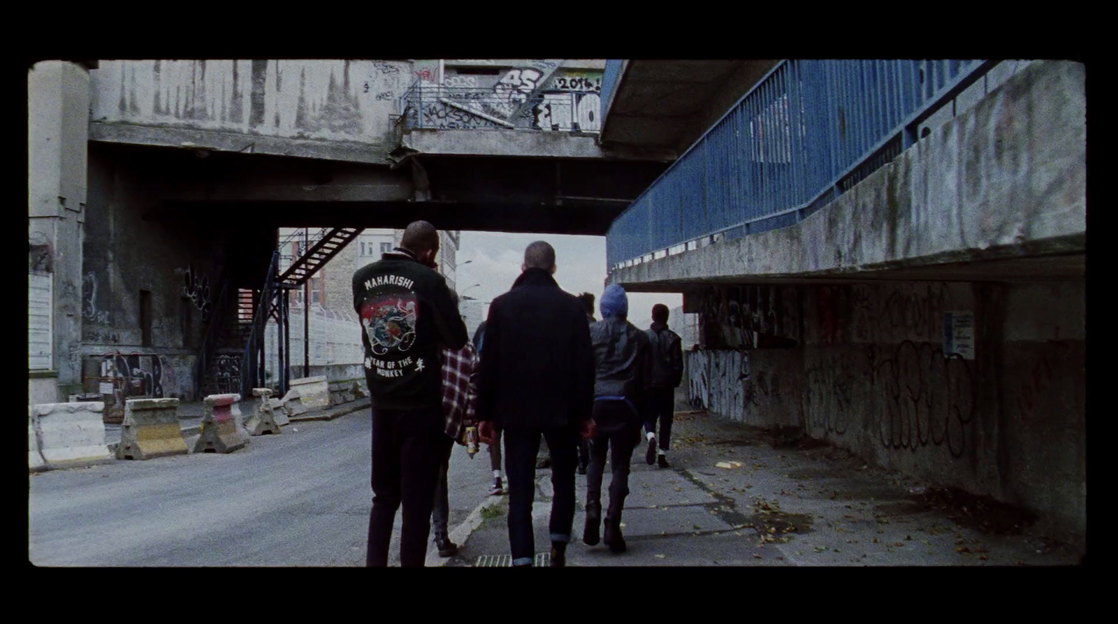 a group of people walking down a street under a bridge