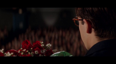 a man with glasses looking at a bouquet of flowers