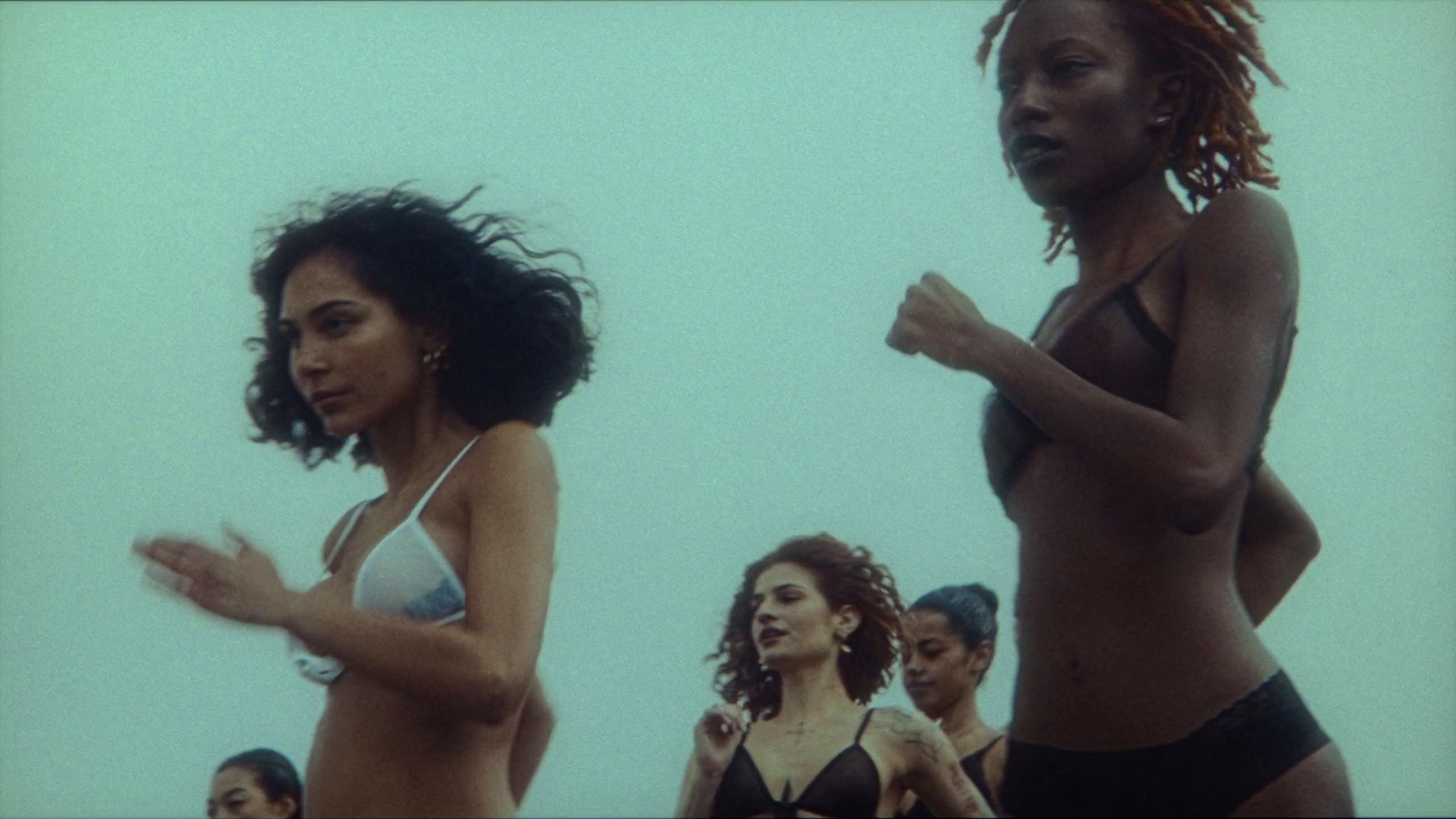 a group of women standing next to each other on a beach