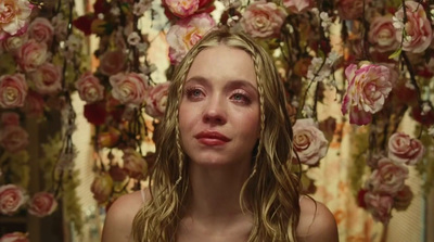 a woman standing in front of a bunch of flowers